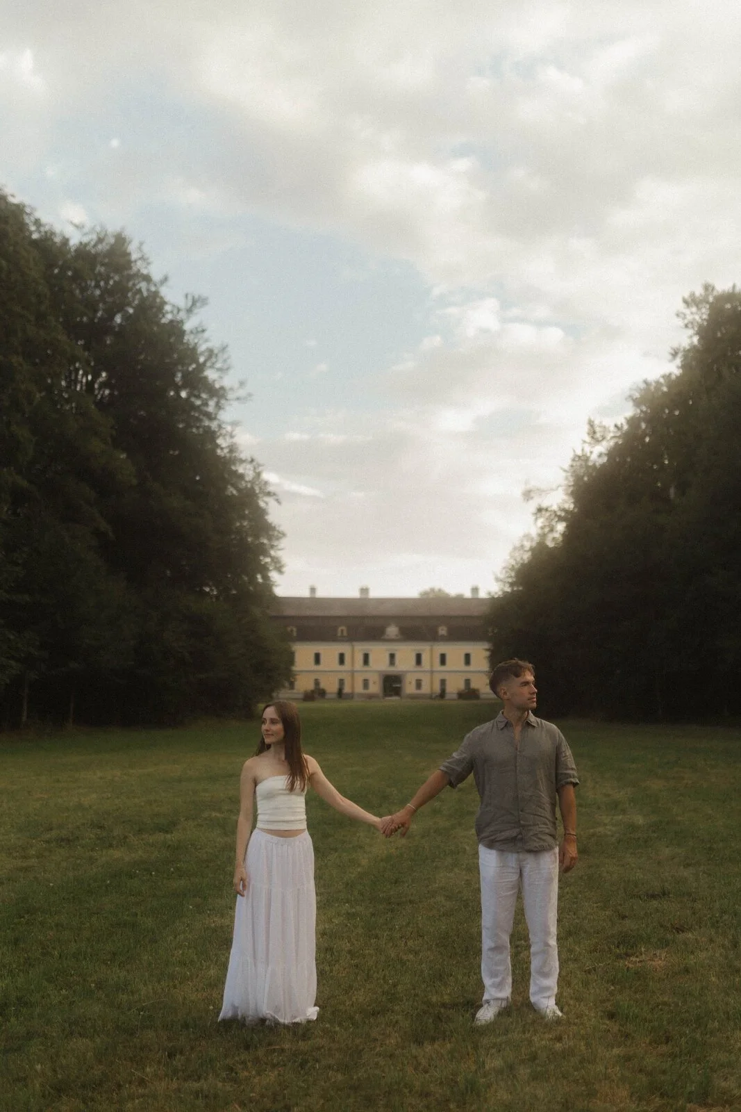 Natalie und Lukas halten im Garten vor dem Schloss Händchen